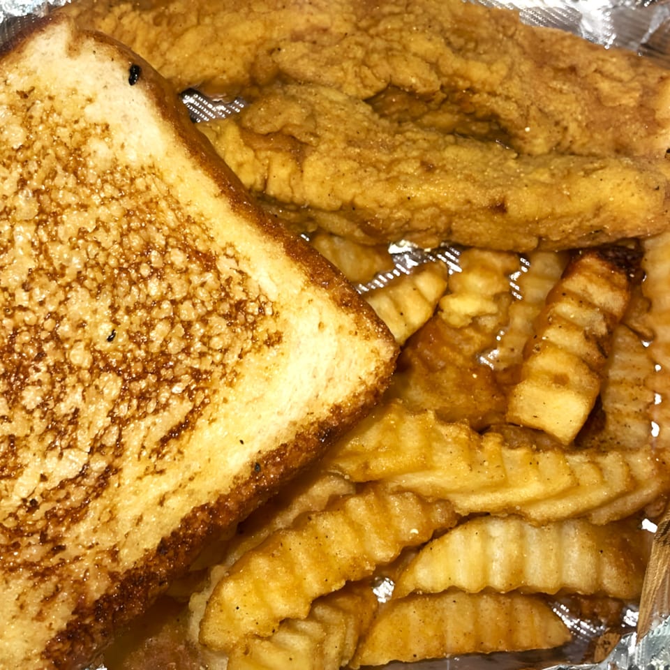 Golden fried fish, crinkle-cut fries, and toasted bread in a takeout container from Take The Wheel.
